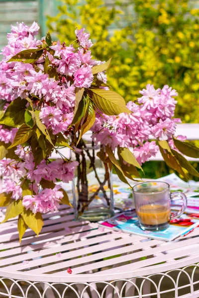 Beautiful and romantic scene in the home garden with a vase of Japanese cherry tree blossoms on the white table