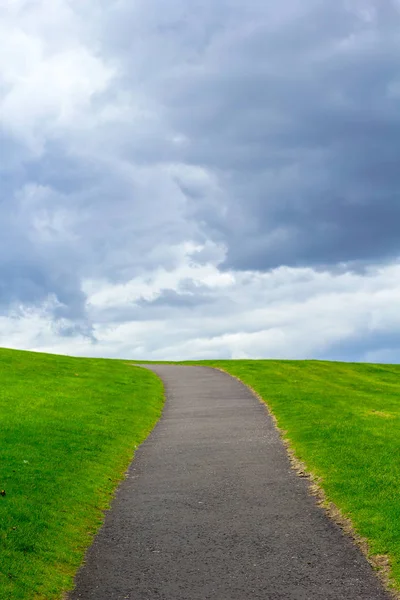 自然背景与一条路径上山 绿草和阴云密布的天空 — 图库照片