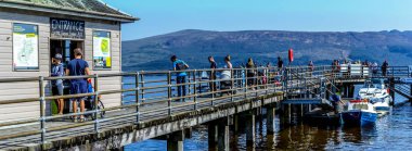 Luss'taki iskelede turistler 25 Ağustos 2019' da İskoçya' nın Loch Lomond kentinde. Yaz'ın sıcak günlerinden birinde insanlar dinlenirken eğleniyor.