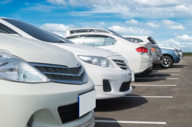 Beyaz bulutlu ve mavi gökyüzü arka planlı büyük bir asfalt otoparka park edilmiş bir araba. Taze ozon ve seyahat teknolojisinin yeşil ortamına sahip açık otopark.