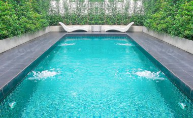 Beyaz rattan sandalyeli modern yüzme havuzu ve yeşil ağaçlı yuvarlak