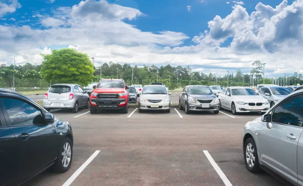 Asfalt otoparka park edilmiş bir araba ve ağaçlarla dolu boş bir park yeri, güzel bulutlu bir gökyüzü ve dağ manzarası. Temiz ozon ve yeşil çevre kavramlı açık hava otoparkı.