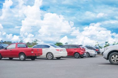 Beyaz bulutlu ve mavi gökyüzü arka planlı araba park yeri. Açık hava otoparkı, taze ozon ve yeşil ulaşım ve teknoloji ortamı.