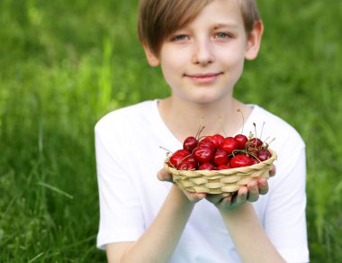 Sevimli sarışın çocuk tatlı kiraz bir sepet ile