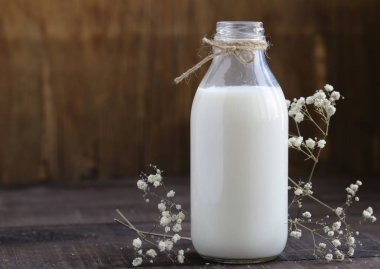 Ahşap bir masa üzerinde bir cam şişe içinde organik süt