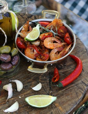 Büyük karidesler, biberli ve otlu bir tavada kızartılıyor.