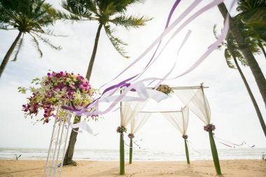 Tropikal kumsalda süslenmiş düğün kemeri, açık deniz düğünü.