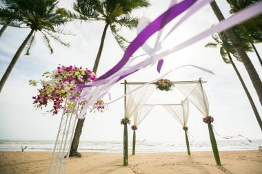 Tropikal kumsalda süslenmiş düğün kemeri, açık deniz düğünü.