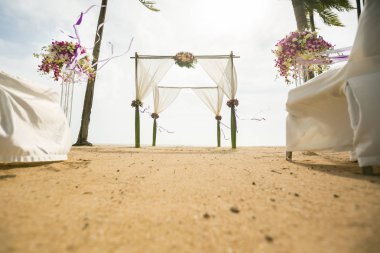 Tropikal kumsalda süslenmiş düğün kemeri, açık deniz düğünü.