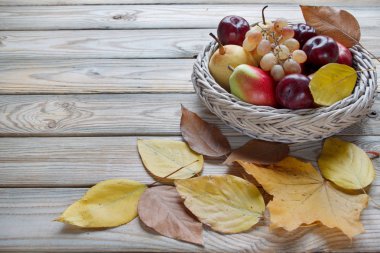 Çeşitli meyve ile Sonbahar natürmort hasır plaka yatıyor. Sonbahar akçaağaç ve diğer yaprakları.