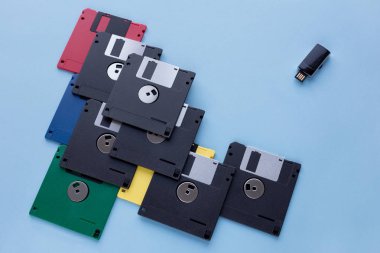 Dijital veri depolama cihazının evrimi. Disketler küçük flash sürücüye karşı. Mavi arka planda yalıtılmış.