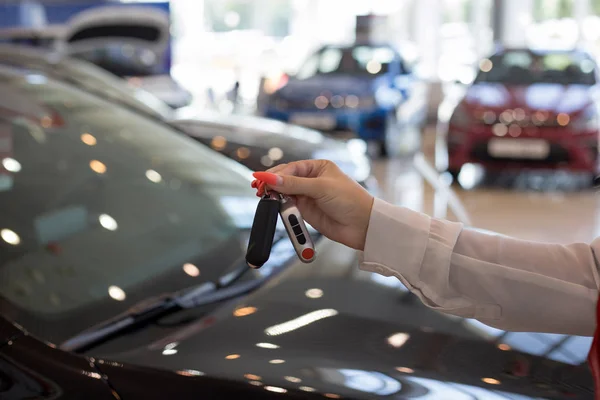 Distribuidora mujer sosteniendo las llaves de un coche nuevo. Vehículos modernos y prestigiosos . — Foto de Stock
