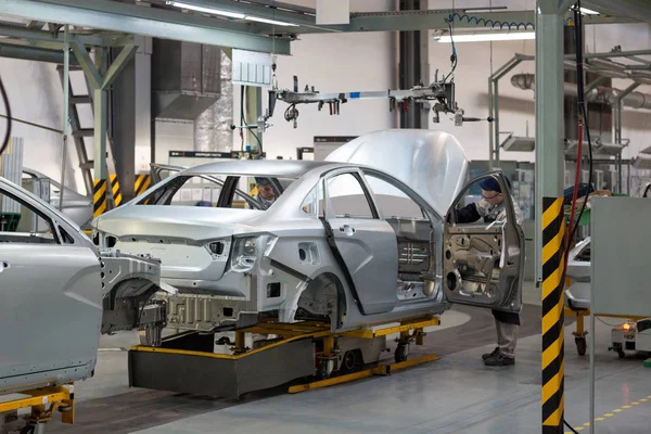 Rusia, Izhevsk - 15 de diciembre de 2018: LADA Automobile Plant Izhevsk. Los trabajadores pusieron puertas en el cuerpo de un coche nuevo . — Foto de Stock