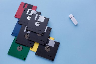 Dijital veri depolama cihazının evrimi. Disketler küçük flash sürücüye karşı. Mavi arka planda yalıtılmış.
