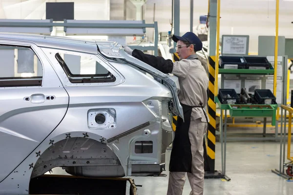 Russia, Izhevsk - December 15, 2018: LADA Automobile Plant Izhevsk. The worker is putting the boot lid to a new car. — Stock Photo, Image