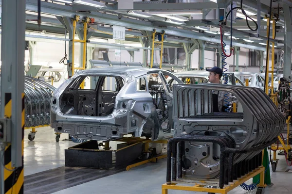 Rusia, Izhevsk - 15 de diciembre de 2018: LADA Automobile Plant Izhevsk. Los trabajadores pusieron puertas en el cuerpo de un coche nuevo . — Foto de Stock