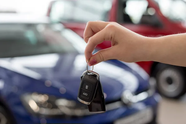 Dealer woman is holding keys to a new car. Modern and prestigious vehicles. — Stock Photo, Image