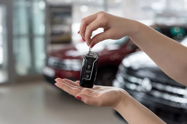 Mujer distribuidor está sosteniendo en sus manos las llaves del coche nuevo. Vehículos modernos y prestigiosos . — Foto de Stock