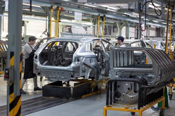 Rusia, Izhevsk - 15 de diciembre de 2018: LADA Automobile Plant Izhevsk. Los trabajadores pusieron puertas en el cuerpo de un coche nuevo . — Foto de Stock