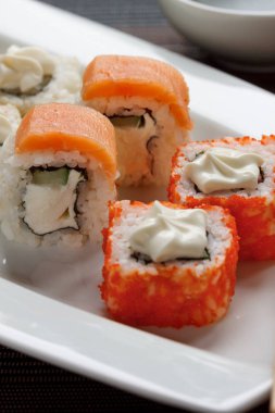 Geleneksel Japon deniz ürünleri, rulo beyaz bir tabak üzerinde yatıyor. Yakın çekim.