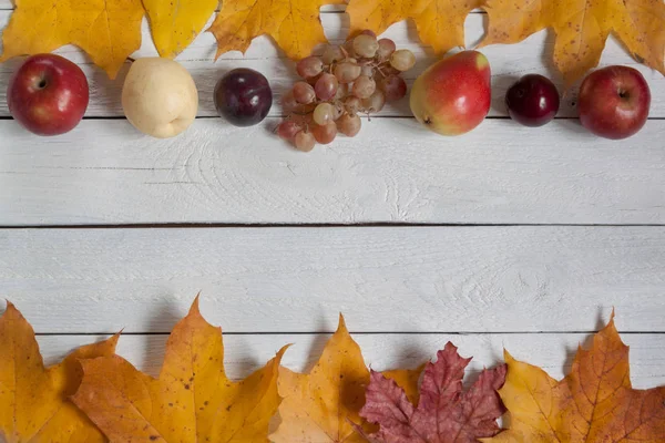 木製の机の上に乾いた葉と様々な果物が横たわっています。秋の静物。テキストの領域をコピーする. — ストック写真