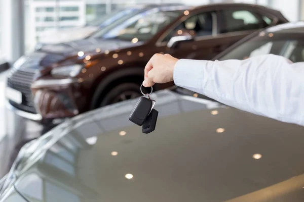 Dealer holding keys to a new car. Modern and prestigious vehicles.