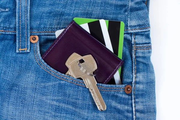 Wallet, credit cards and keys to the house on a keychain are lying in a side pocket of blue jeans.
