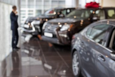 Müşteri yeni bir araba almayı düşünüyor. Modern ve prestijli araçlar. Bokeh efektli temalı bulanıklık arka planı.