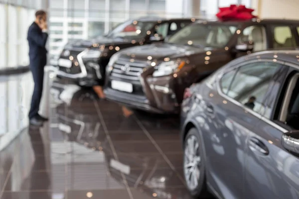 Customer ponders buying a new car. Themed blur background with bokeh effect. Modern and prestigious vehicles. — Stock Photo, Image