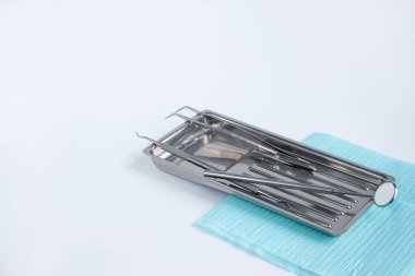 Diş hekimi için bir grup alet ve aksesuar tıbbi tepside yatıyor. Beyaz arkaplanda izole.