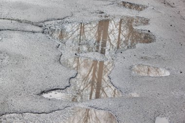 Çukur suyla dolu, asfalt bir yol. Tehlikeli yol yatağı yok edildi..