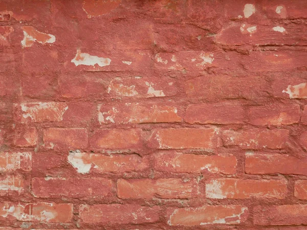 Detail of old brick wall with colored in red and shelled paint layers