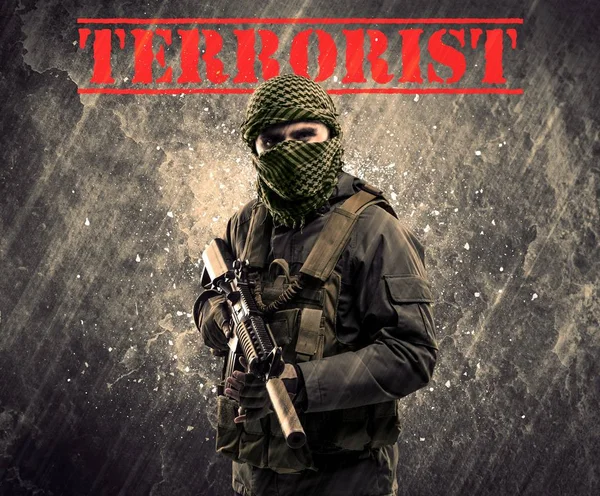 Eski arka plan üzerinde terörist işareti ile tehlikeli maskeli ve silahlı bir adam — Stok fotoğraf