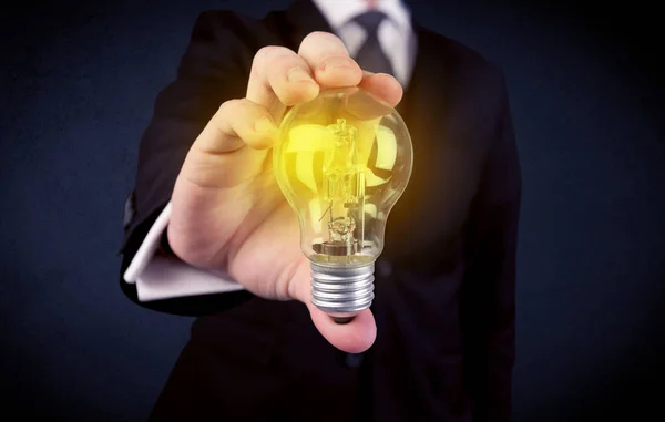 Man in suit holding a glowing yellow light bulb — Stock Photo, Image