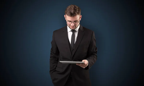 Businessman holding tablet with dark background — Stock Photo, Image