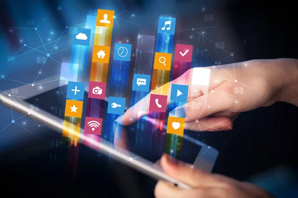 Hand using tablet with application icons flying around — Stock Photo, Image