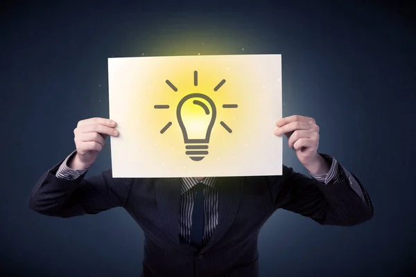 Businessman holding paper with lightbulb — Stock Photo, Image