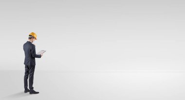 Boş bir alanda duran ve bir plan tutan mimar