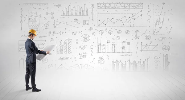 Ingenjören hålla en plan och stående med grafer, diagram och rapporter i bakgrunden — Stockfoto