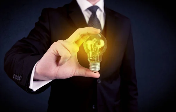 Man in suit holding a glowing yellow light bulb — Stock Photo, Image