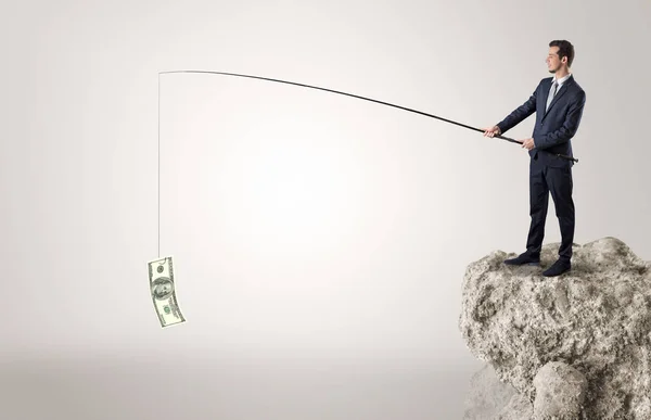 Businessman fishing dollar from a rock — Stock Photo, Image