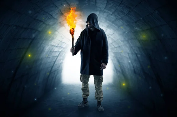 Man promenader med brinnande flambeau i en mörk tunnel — Stockfoto