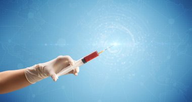 Kadın doktor elinde şırınga tutuyor.