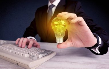 parlak sarı ampul tutan takım elbiseli adam