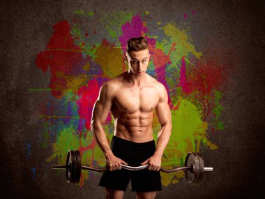 Ağırlık kaldırma ve onun sıcak vücut kasları önünde bir kentsel boyalı duvar kavramı ile gösterilen bir kas genç vücut geliştirmeci