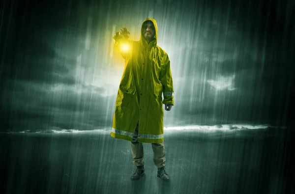 Raincoated man walking in storm with glowing lantern in his hand