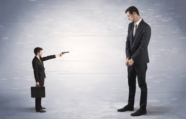 Small businessman shooting giant businessman — Stock Photo, Image