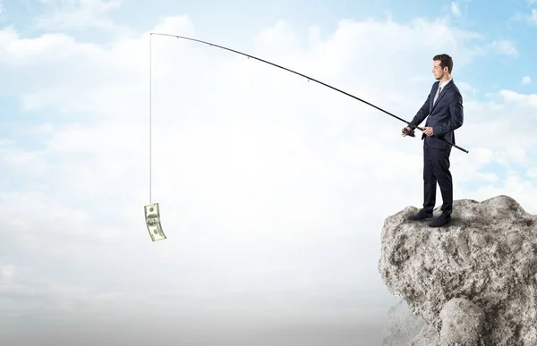 Hombre de negocios pescando dólar desde una roca — Foto de Stock