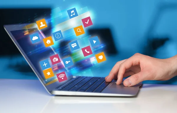 Mão usando laptop com ícones de aplicação coloridos e símbolos conceito — Fotografia de Stock