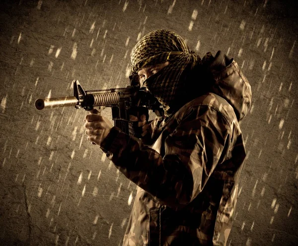Perigoso soldado terrorista fortemente armado com máscara em fundo chuvoso grungy — Fotografia de Stock